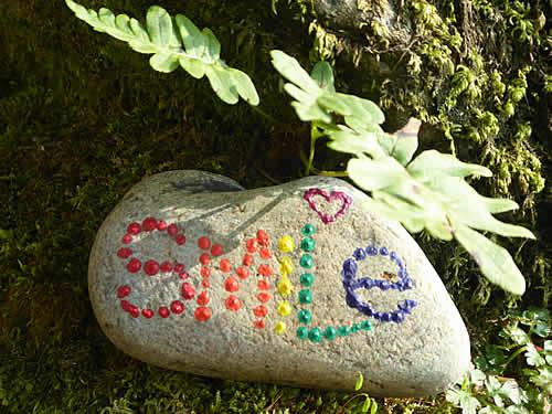 Pebble with word smile painted in rainbow spots